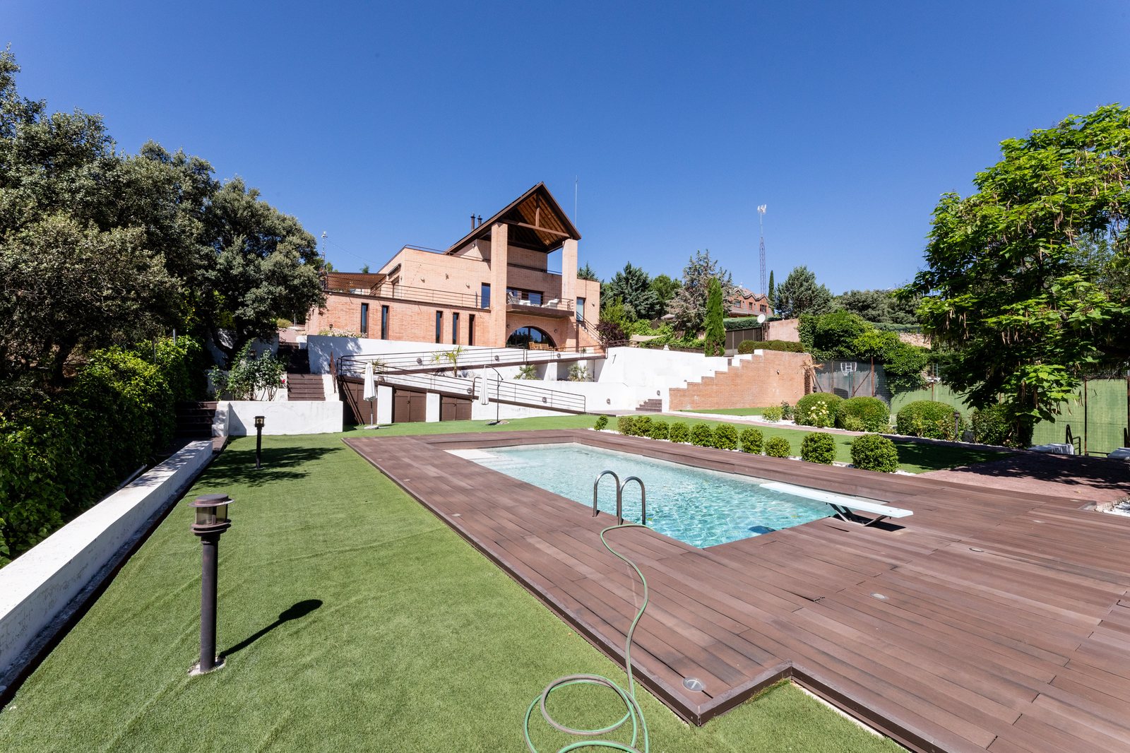 Piscina con vista exterior del chalet y pórtico triangular
